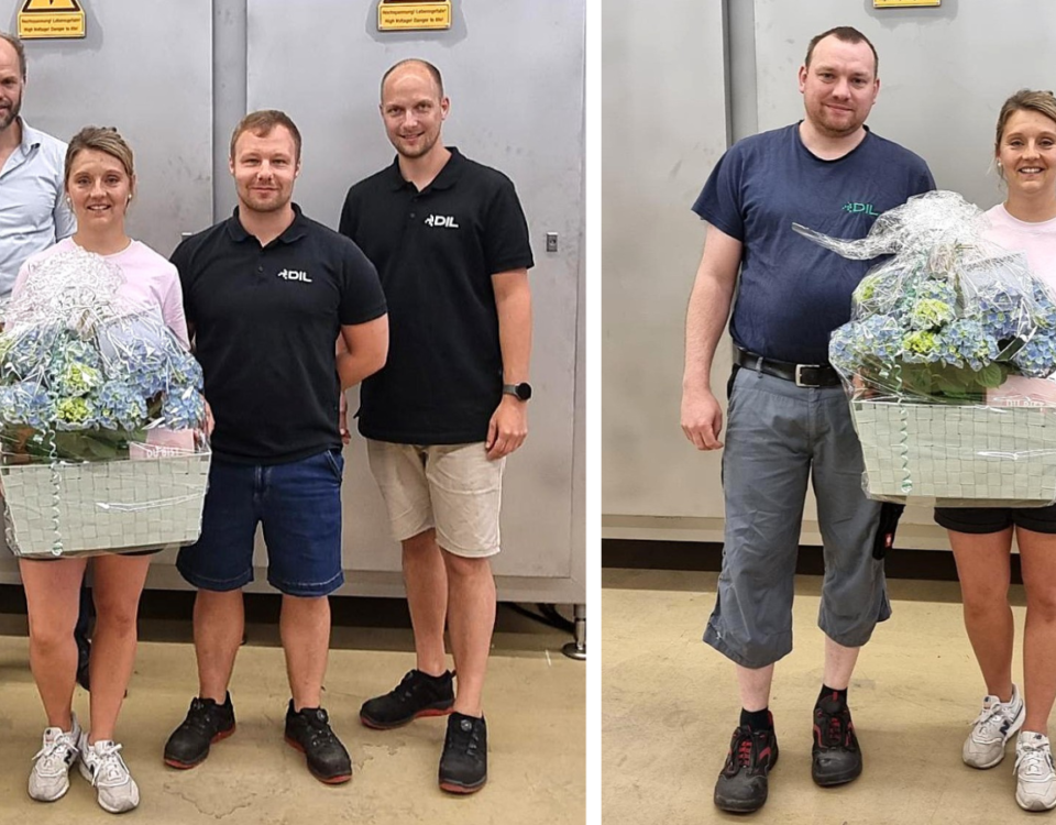 Zwei nebeneinander platzierte Fotos zeigen mehrere Mitarbeitende der DIL Engineering GmbH in der Fertigungshalle. In der Mitte steht jeweils eine Frau mit einem großen, in Folie verpackten Präsentkorb mit blauen Hortensien. Auf dem linken Foto posiert sie mit 3 Kolleginnen und Kollegen aus ihrem Team und dem Geschäftsführer, auf dem rechten Foto mit einem Kollegen aus der Fertigung. Einige Personen tragen Arbeitskleidung mit DIL-Logo.